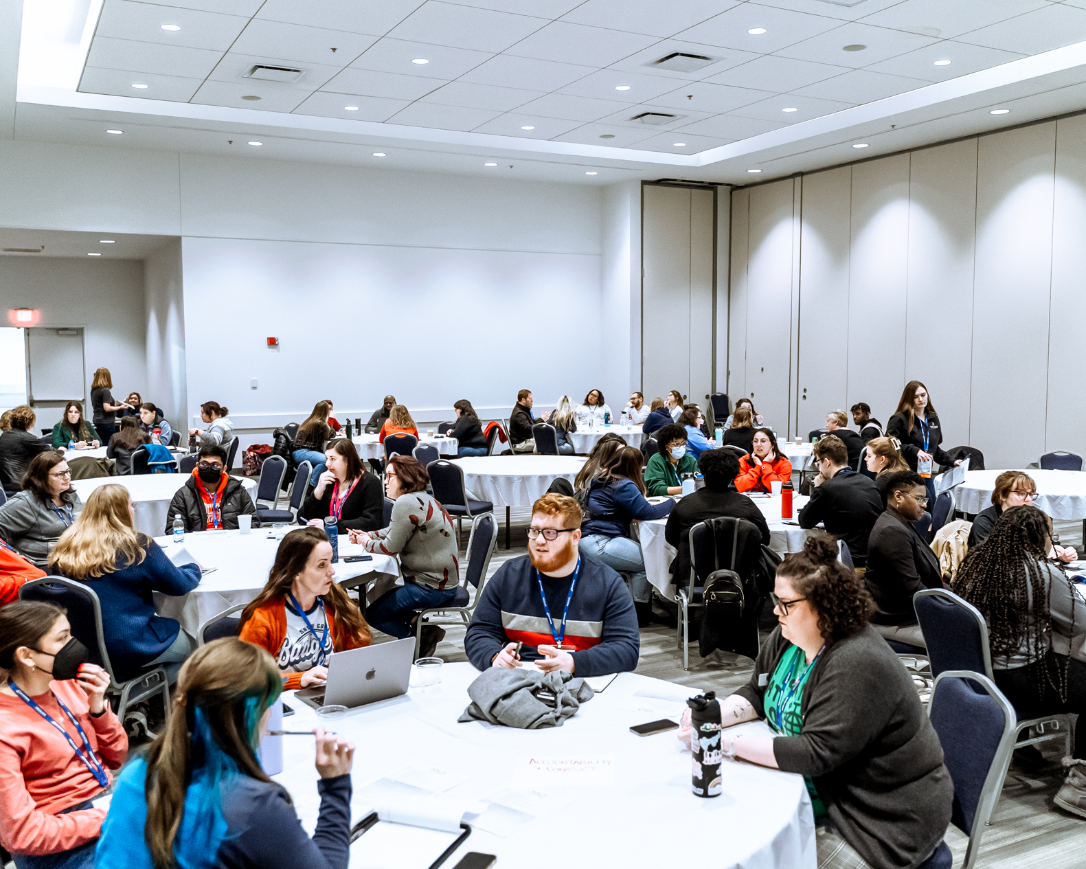 Photo of the Forum for Student Org Advisors. Campus staff members sitting at round tables engaging in discussion.